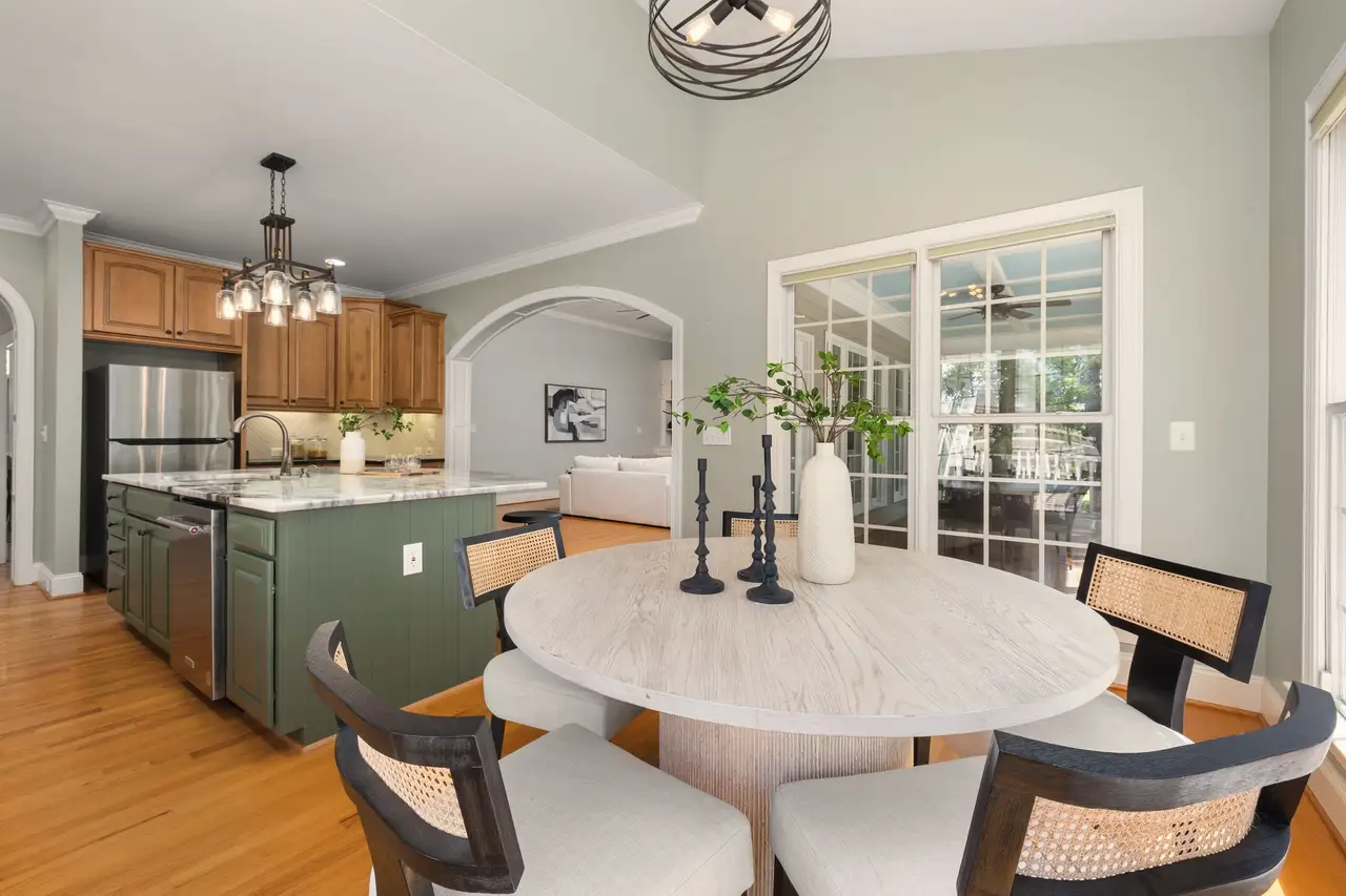 Remodelled kitchen with a green island, pendant lights and a round dining table by the window
