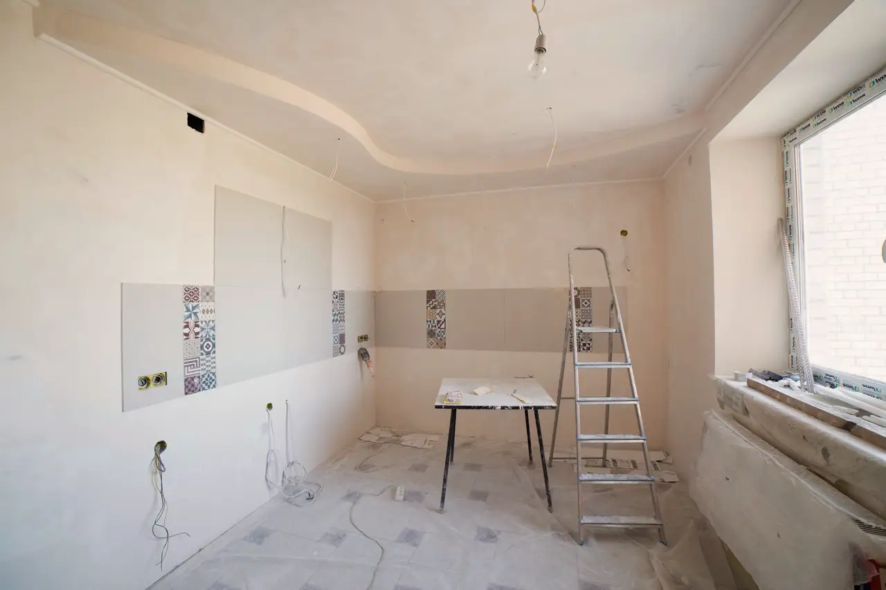 Room under renovation with a ladder, taped floor and new cabinets going in