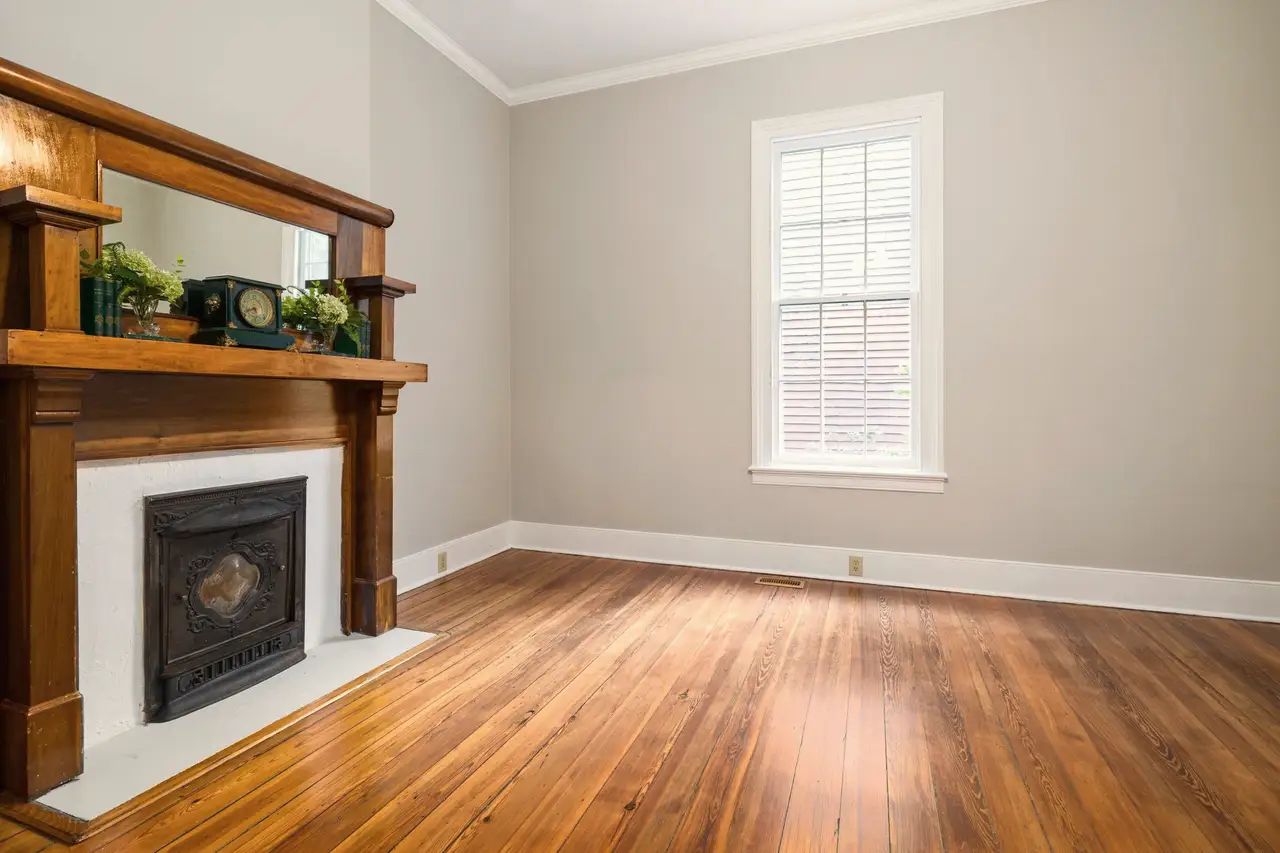 Restored living room with a carved wood fireplace mantel and refinished fir floors