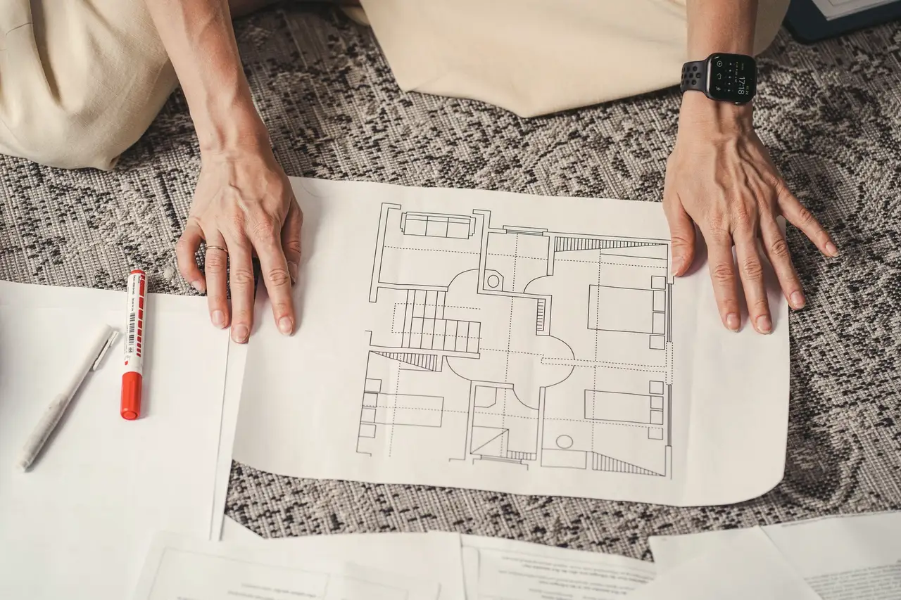 Hands resting on a printed floor plan during a design meeting